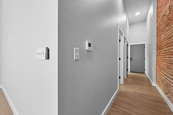 A hallway with a brick wall on the side and a door at the end.